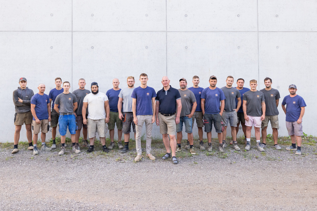 Teamfoto im Arbeitsgewand vor betonwand